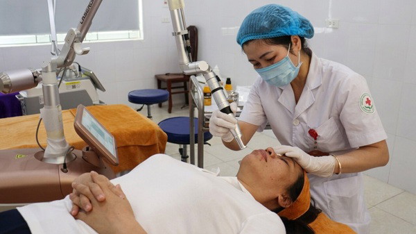 Bác sĩ đang thực hiện thủ thuật chăm sóc da cho người bệnh